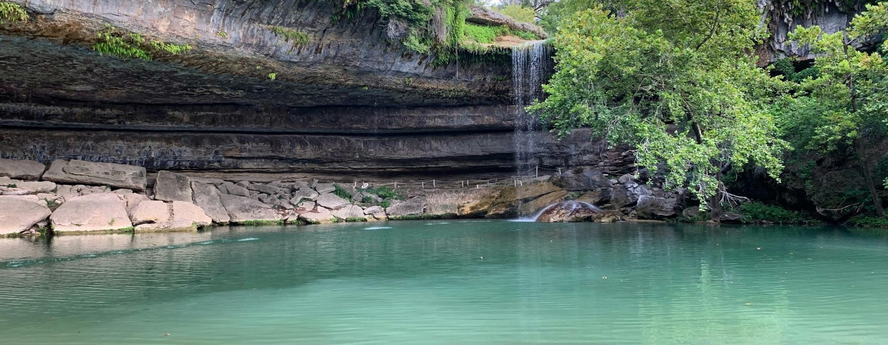 a body of water with a rocky cliff and trees around it